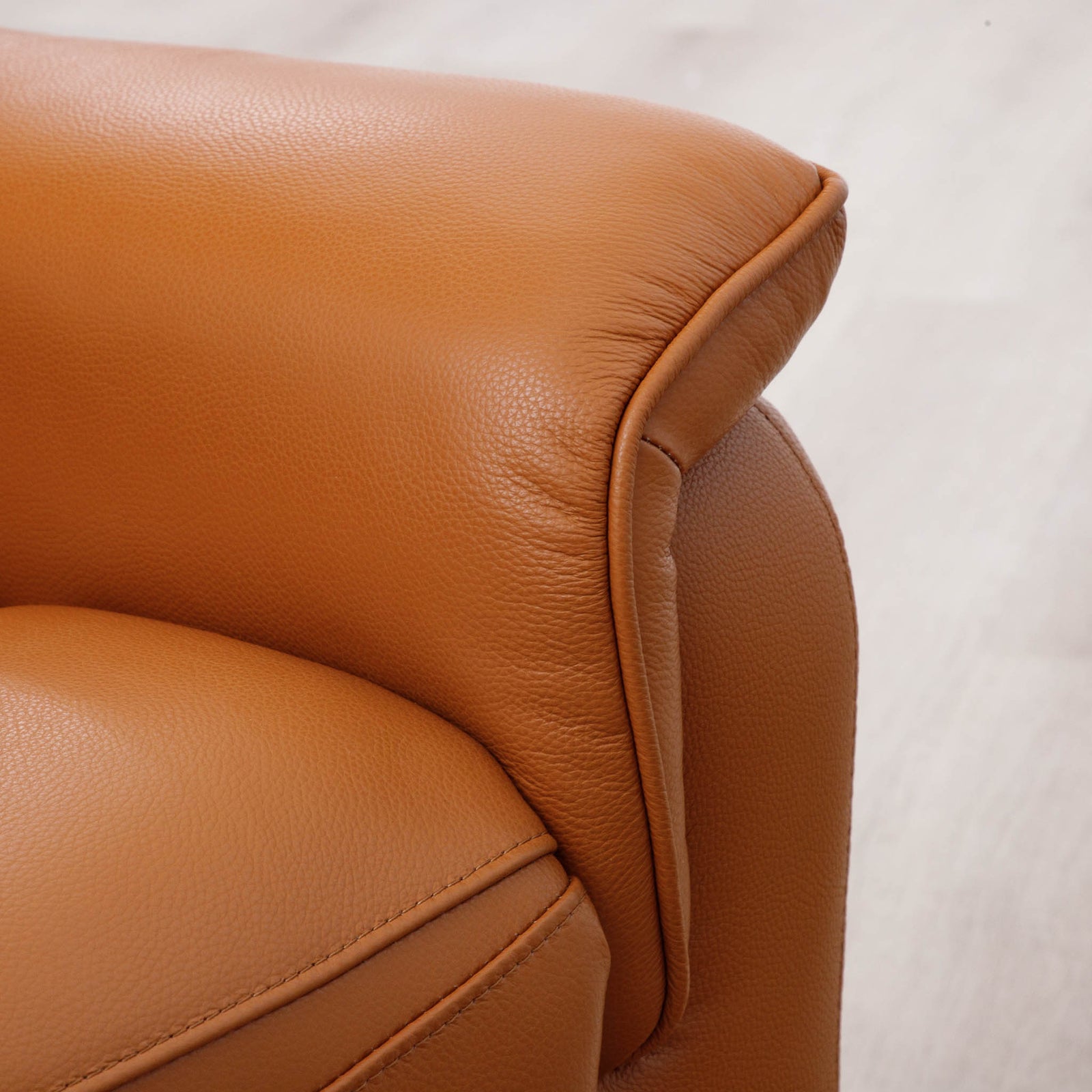 Close-up of the Leather Gallery Carter 1 Seater Leather Recliner Chair in Tan, showing the leather grain, armrest corner, and curved piping detail.