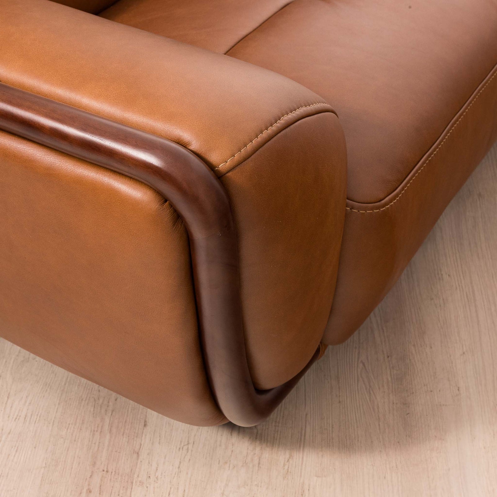 Close-up of the Leather Gallery Zuri 3 Seater Leather Couch in Czar Pecan, showing the armrest and curved dark wood trim.