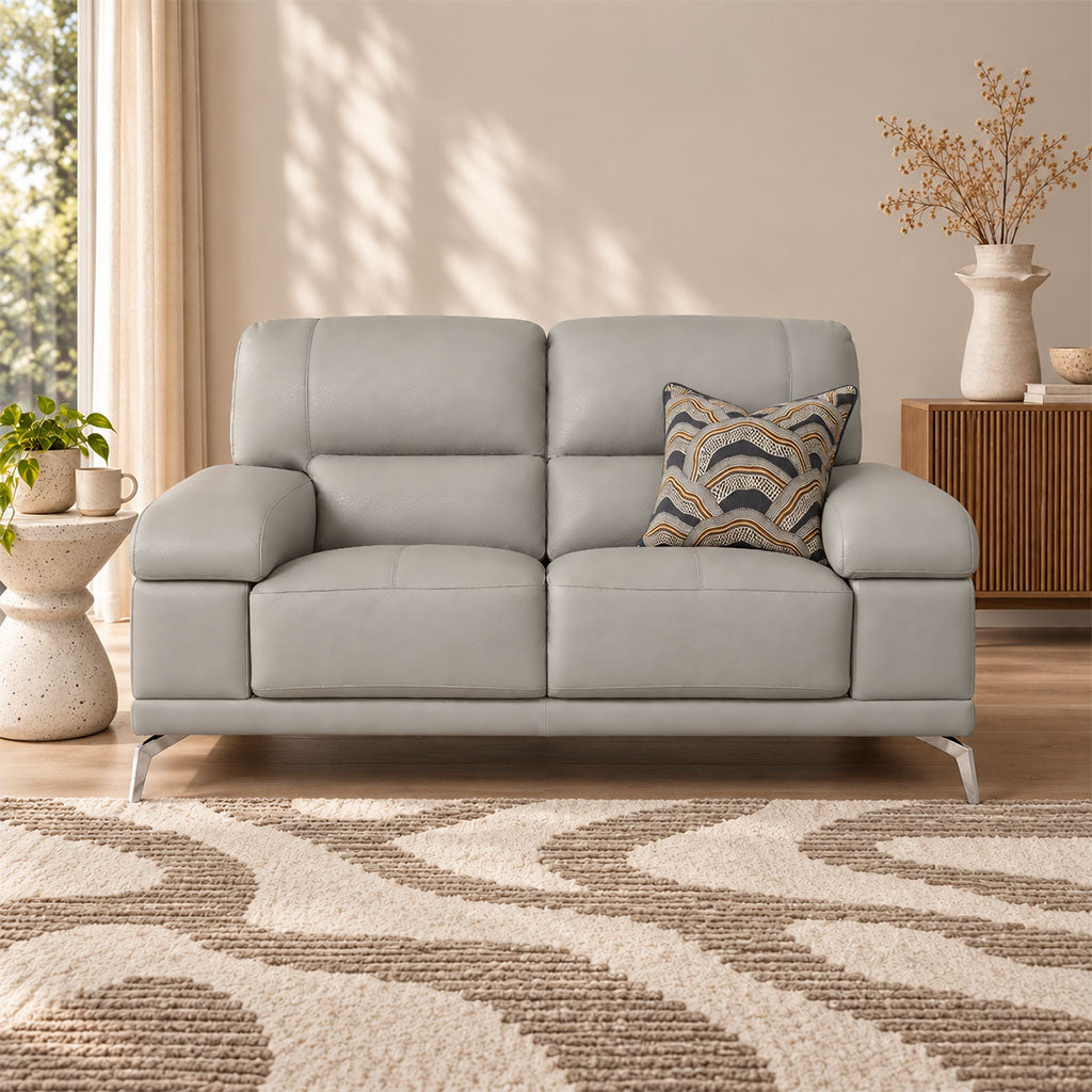 Leather Gallery Adaline 2 Seater Leather Couch in Manatee Grey, featuring light grey leather upholstery and a patterned accent cushion in a modern living room.
