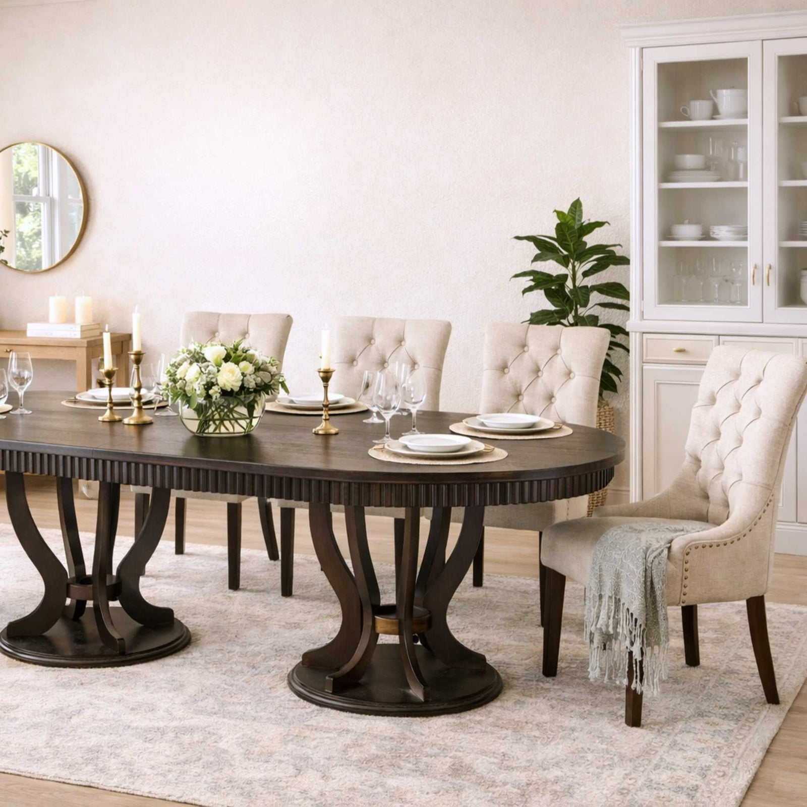 Large Sorrento 8-seater dining table with a fluted wood top and dark birdcage leg design, paired with Duchess tufted fabric upholstered dining chairs in a light cream color.