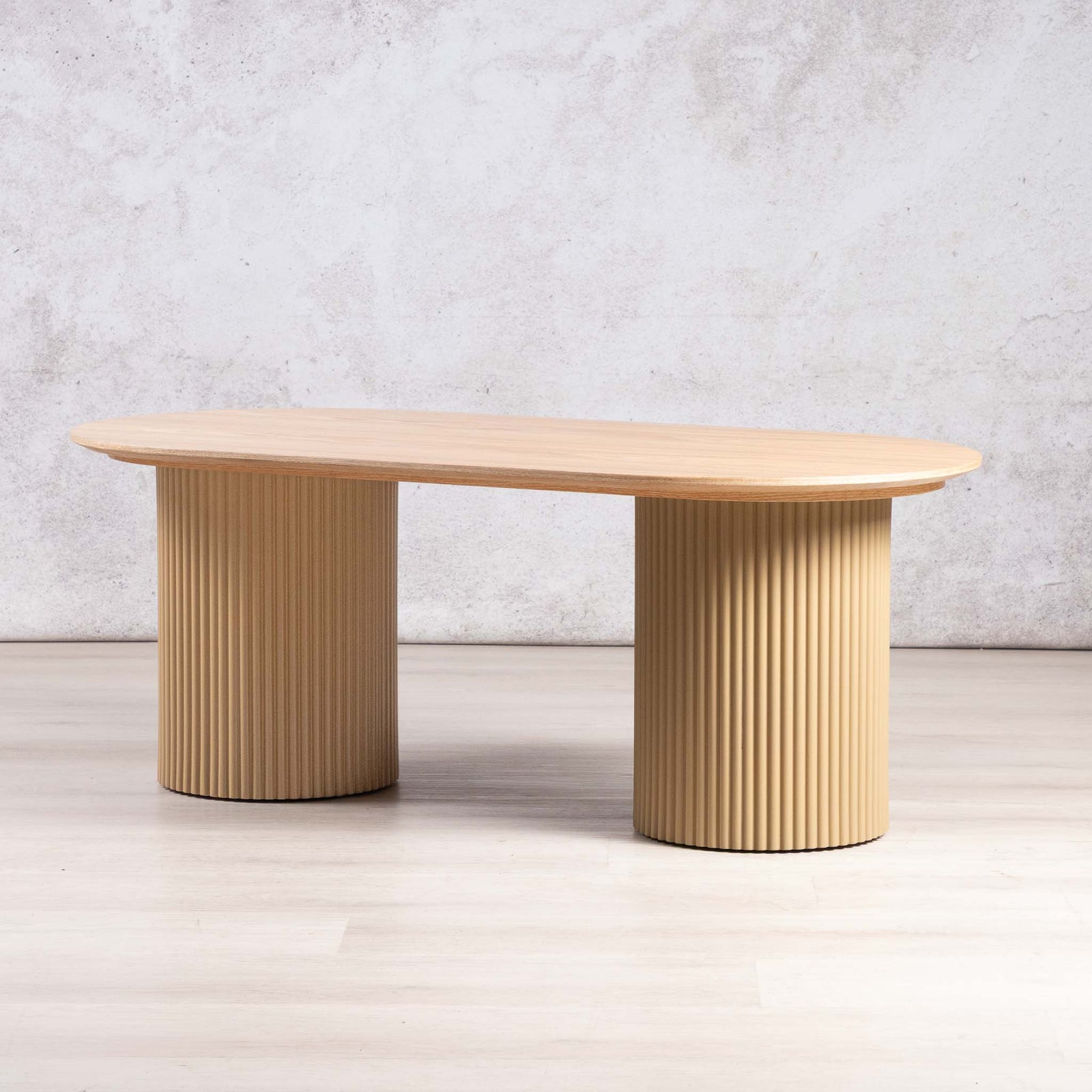 Sybil racetrack-shaped coffee table with fluted wood pedestal bases.