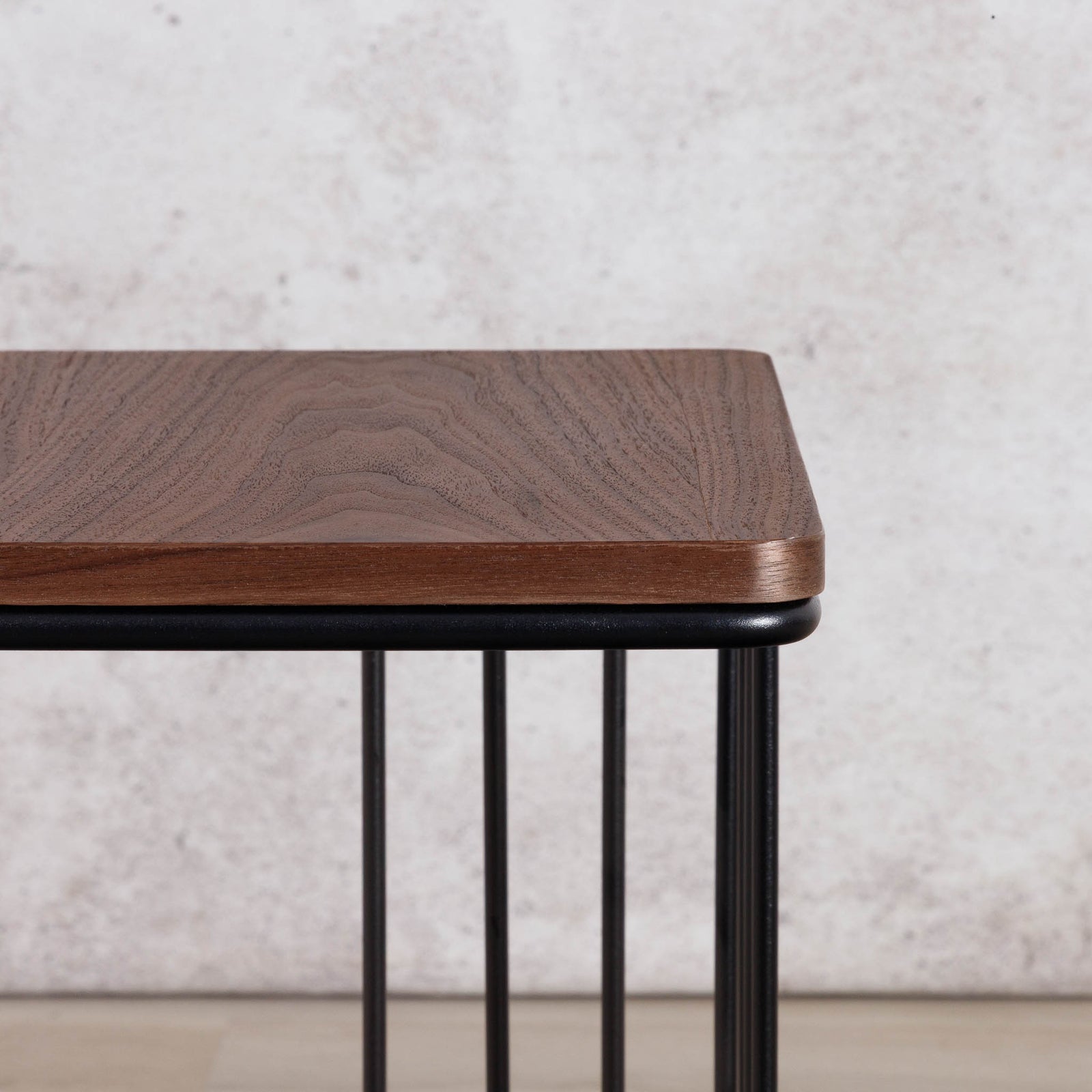 Close-up of the Gallery Everyday Camila Side Table in Walnut, showing the rounded wood-grain tabletop and black metal slatted base.