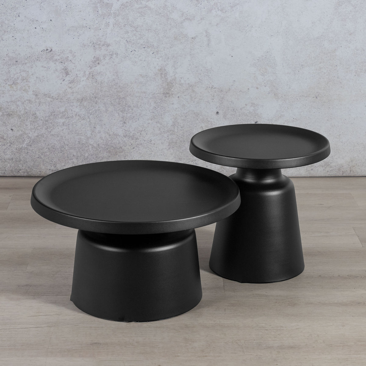 Gallery Everyday Minerva Coffee Table - Black Set of 2, featuring two minimalist black pedestal tables on a wooden floor.