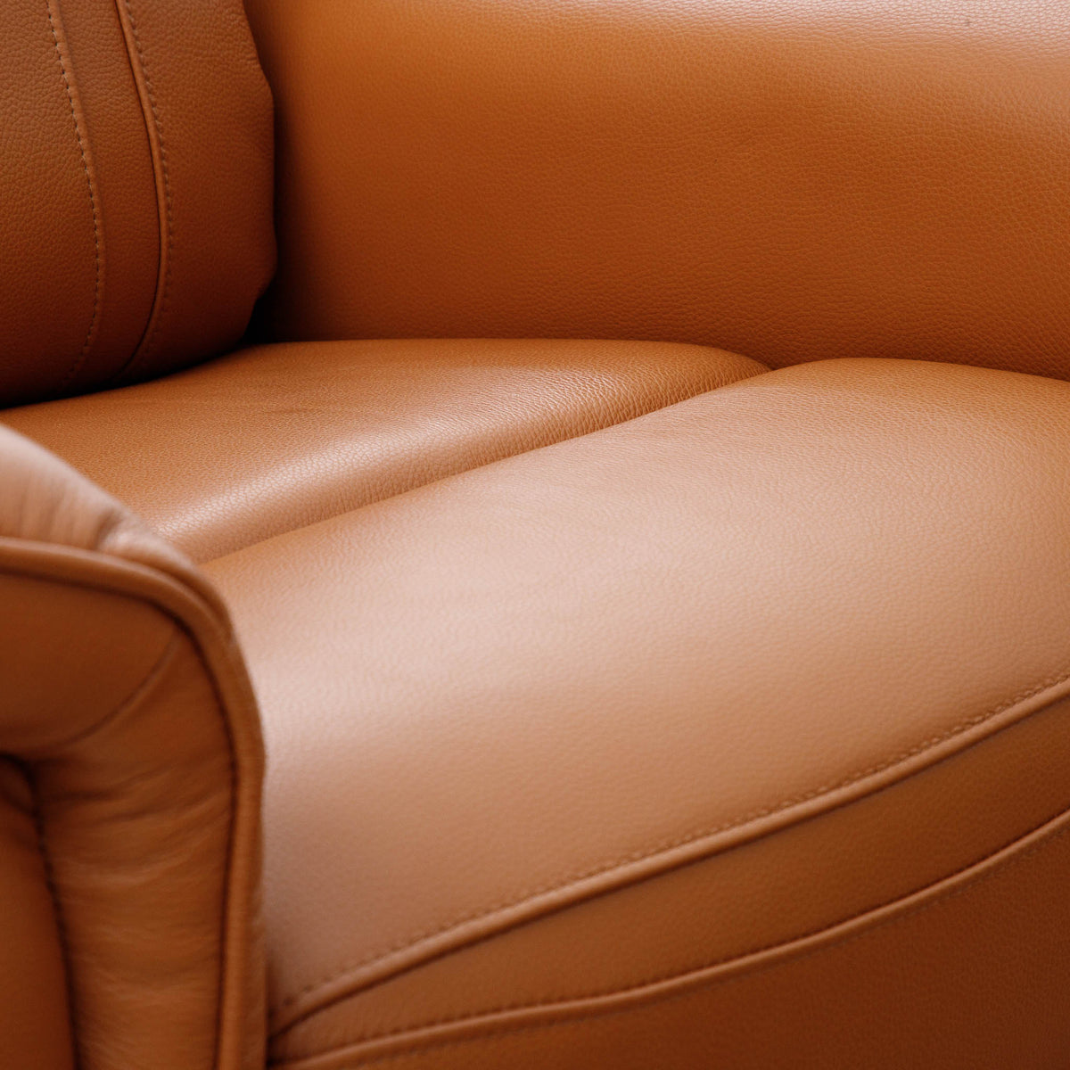 Close-up of the Leather Gallery Carter 1 Seater Leather Recliner Chair in Tan, showing the smooth leather texture, seat, armrest, and stitching detail.