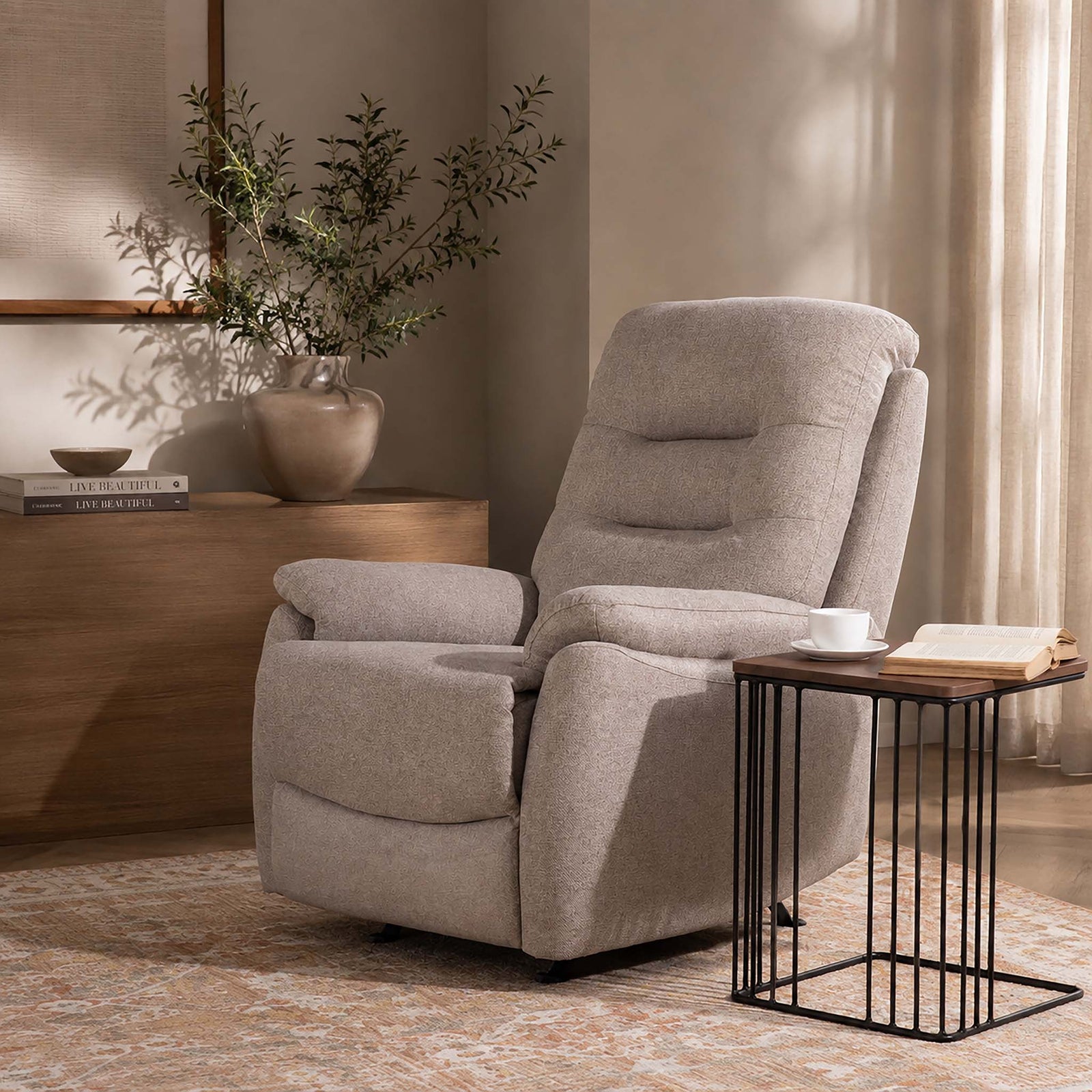 Leather Gallery Dallas Fabric Rocker Recliner Chair in Beige, styled beside a black wire side table in a modern living room.