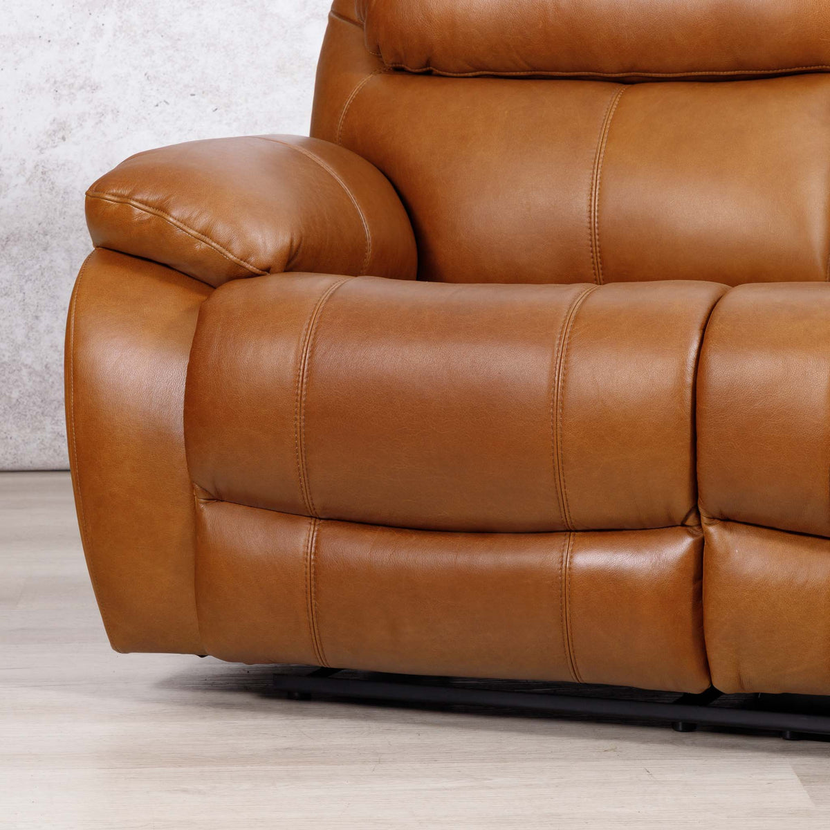 Close-up of the Leather Gallery Kuta 3 Seater Leather Recliner in Czar Pecan, showing the padded armrest, tufted stitching, and dark metal base.