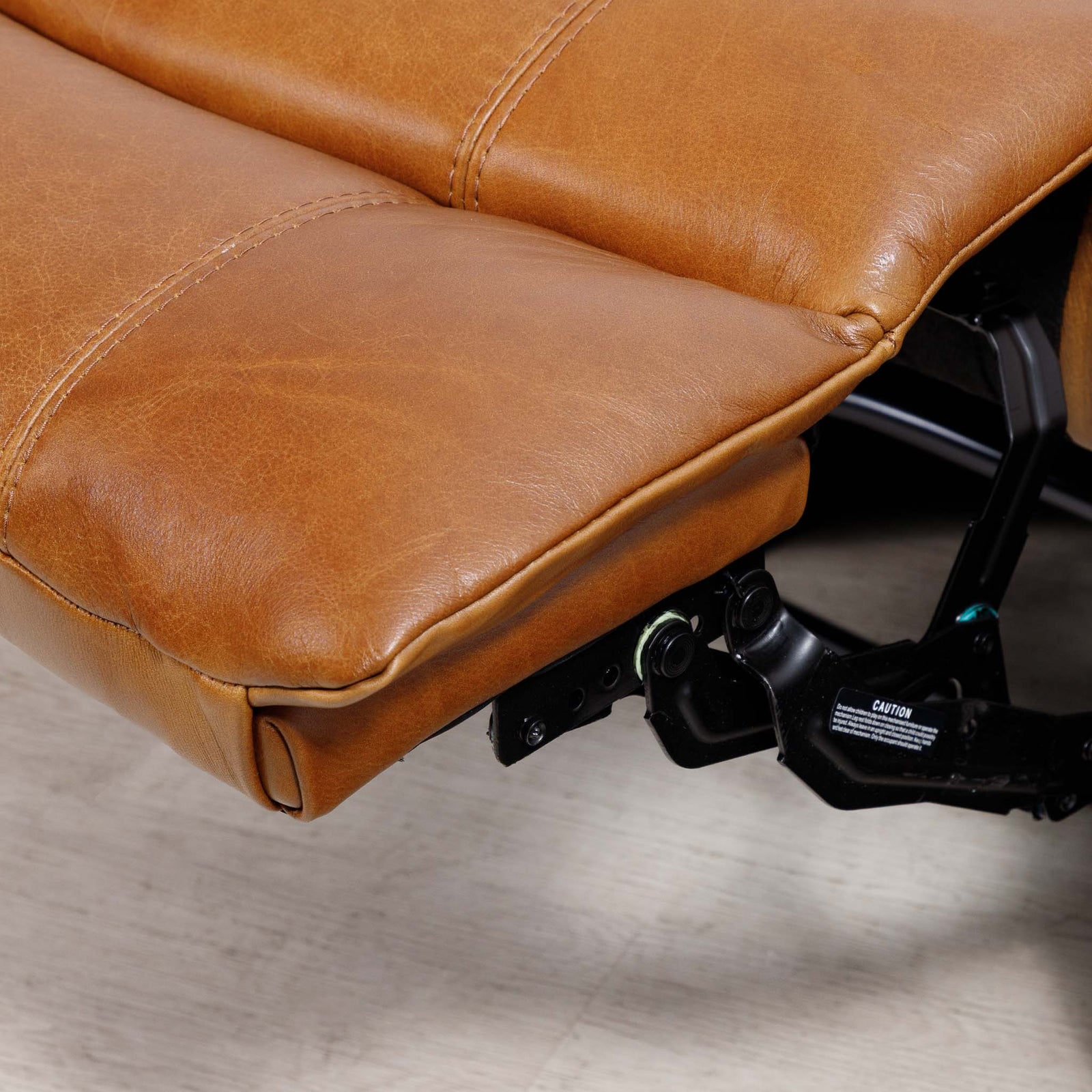 Close-up of the Leather Gallery Kuta 1 Seater Leather Recliner in Czar Pecan, showing the leather cushion and black mechanical support hardware.