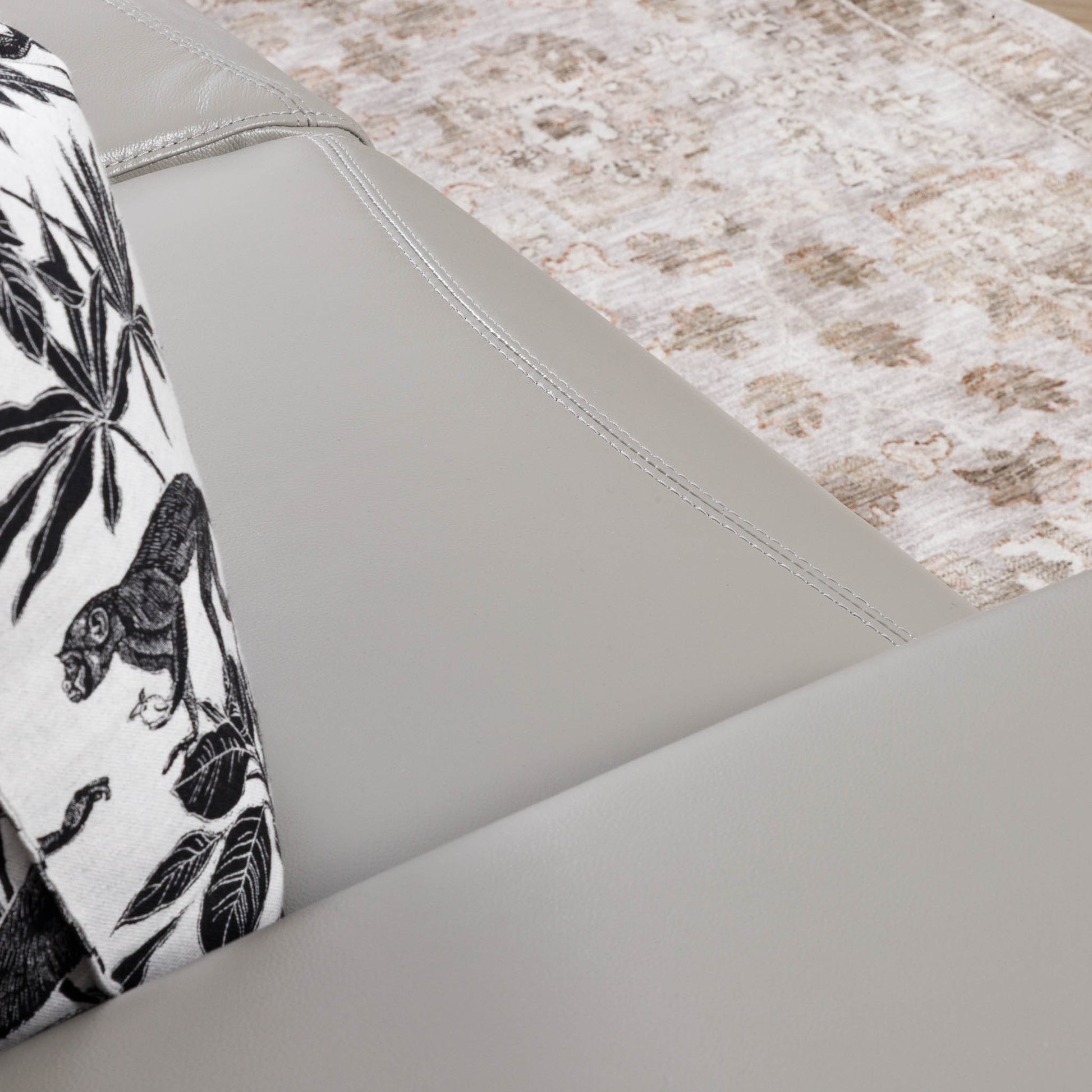 Close-up of the Leather Gallery Tobago 2 Seater Leather Couch in Grey, showing the upholstered corner with a black-and-white patterned cushion.