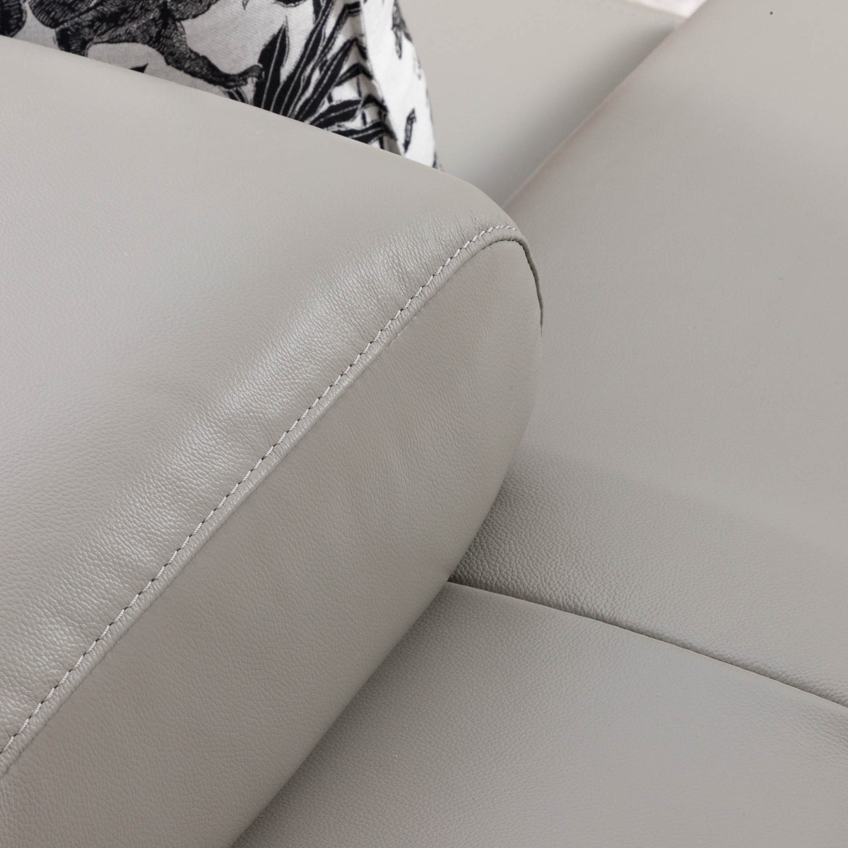 Close-up of the Leather Gallery Tobago 2 Seater Leather Couch in Grey, showing the stitched leather corner with a black-and-white patterned cushion.