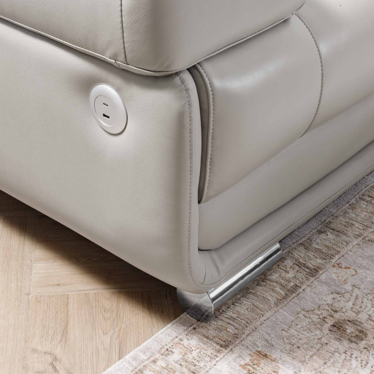 Close-up of the Leather Gallery Tobago 5 Seater Leather L Shape Couch in Grey, showing the side outlet, seat base, and metal support leg.