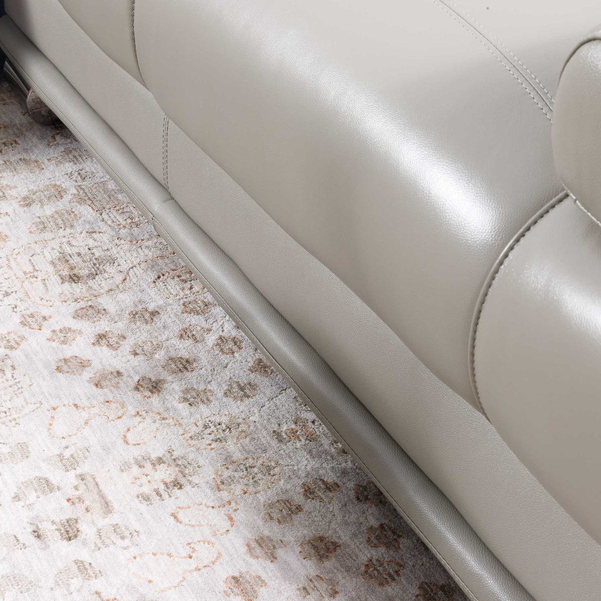 Close-up of the Leather Gallery Tobago 5 Seater Leather L Shape Couch in Grey, showing the leather corner resting on a patterned area rug.