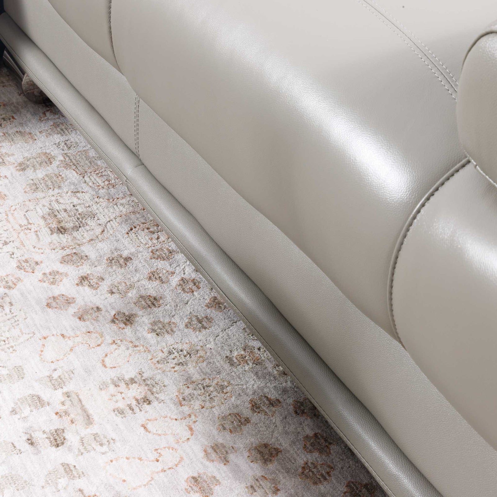 Close-up of the Leather Gallery Tobago 5 Seater Leather L Shape Couch in Grey, showing the leather corner resting on a patterned area rug.