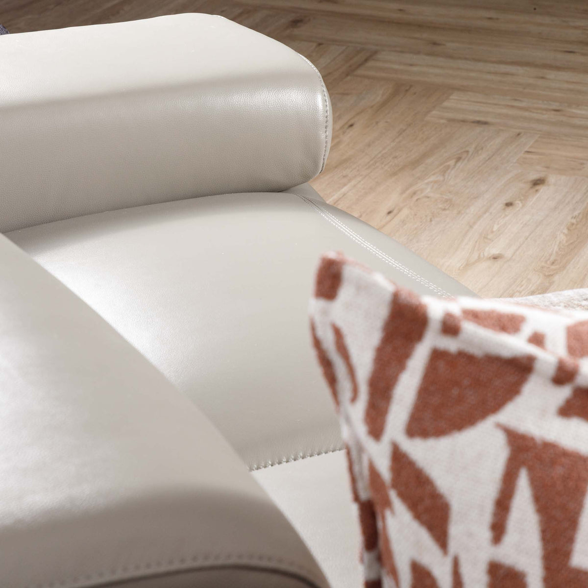 Close-up of the Leather Gallery Tobago 5 Seater Leather L Shape Couch in Grey, showing the leather armrest with a patterned cushion.