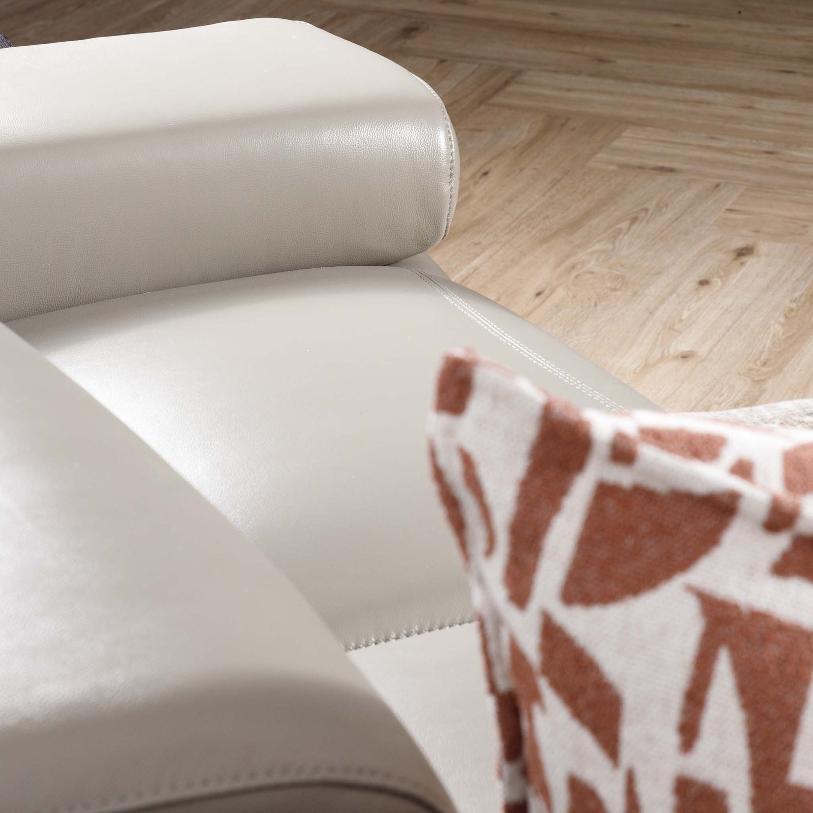 Close-up of the Leather Gallery Tobago 5 Seater Leather L Shape Couch in Grey, showing the leather armrest with a patterned cushion.