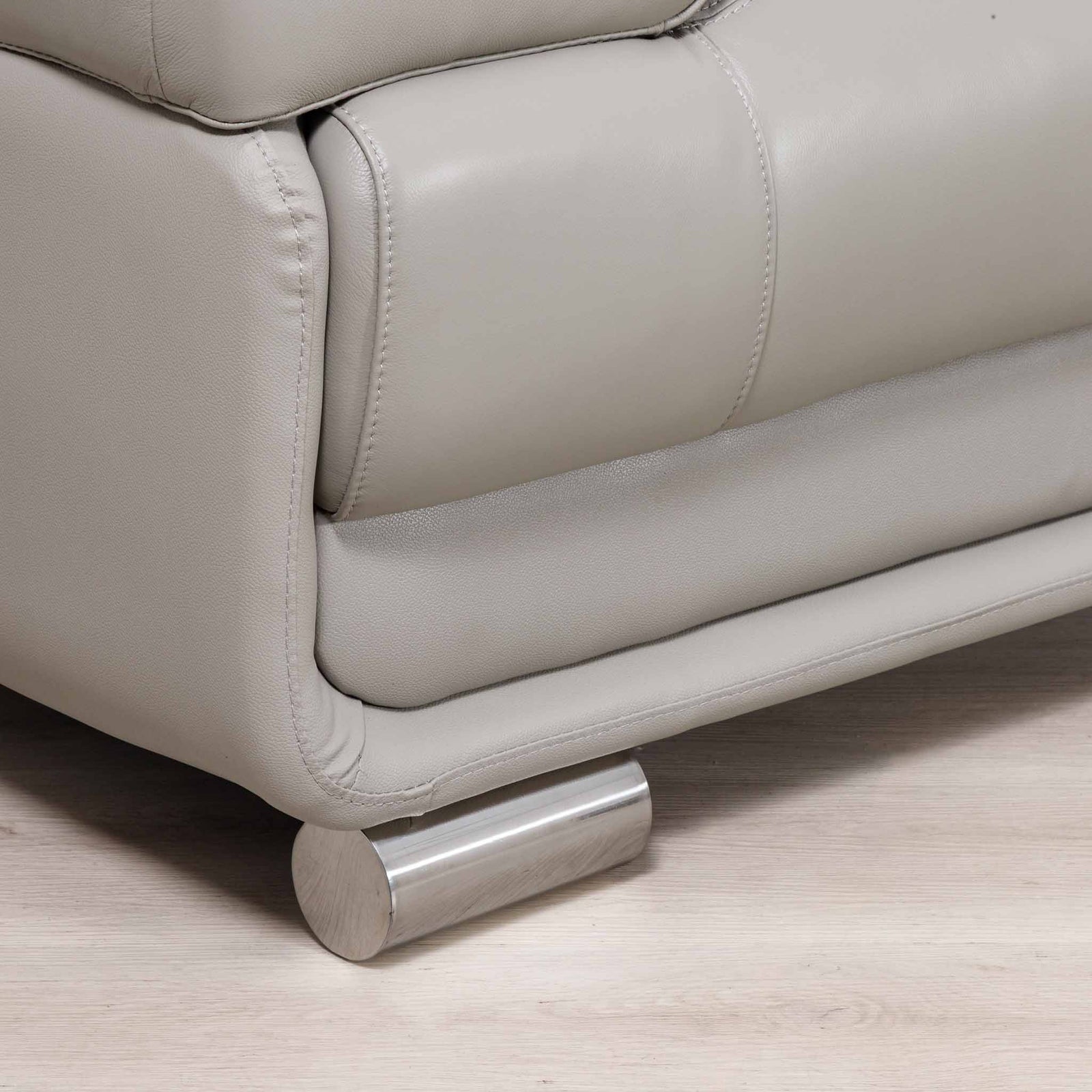 Close-up of the Leather Gallery Tobago 5 Seater Leather L Shape Couch in Grey, showing the leather corner and cylindrical brushed metal foot.