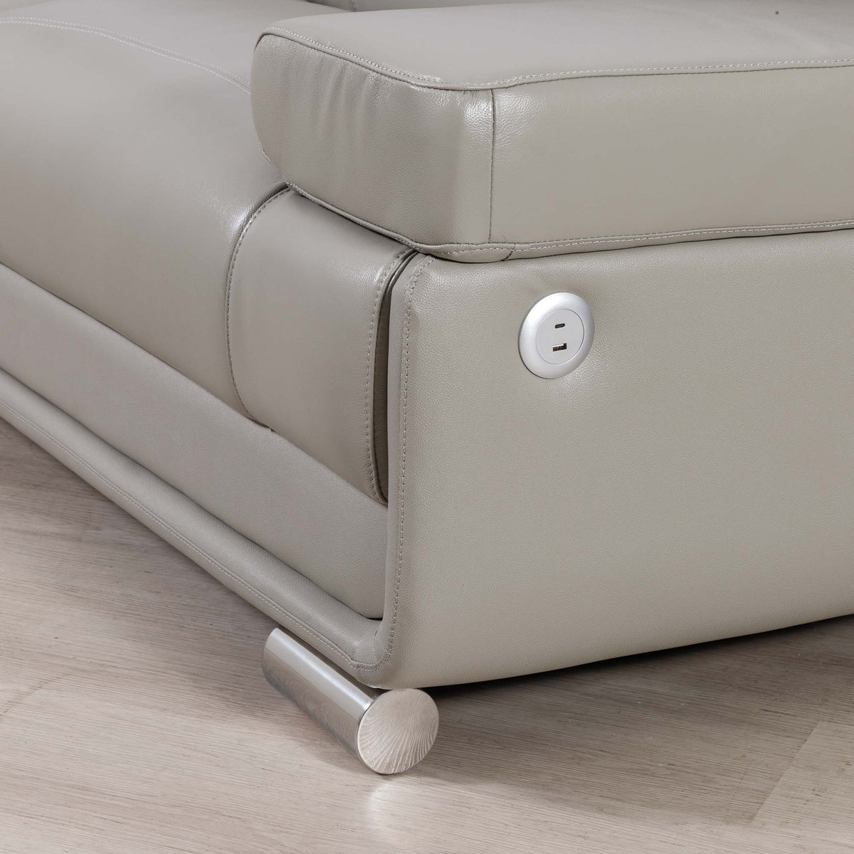 Close-up of the Leather Gallery Tobago 5 Seater Leather L Shape Couch in Grey, showing USB and USB-C charging ports and a cylindrical metal leg.