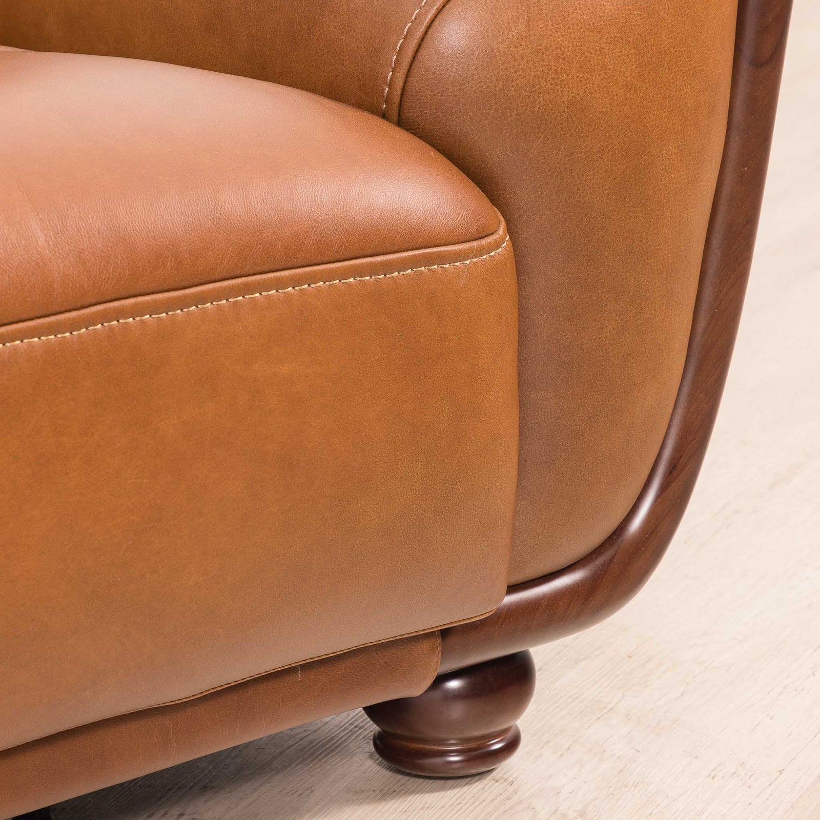 Close-up of the Leather Gallery Zuri 3 Seater Leather Couch in Czar Pecan, showing dark wood trim and turned wooden legs.