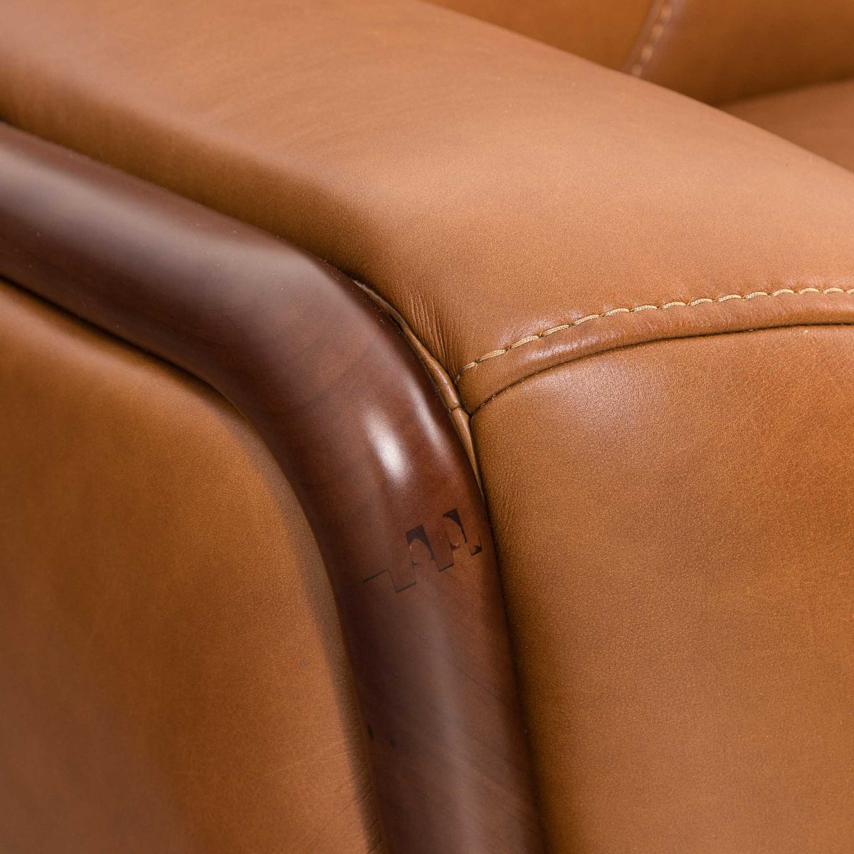 Close-up of the Leather Gallery Zuri 1 Seater Leather Couch in Czar Pecan, showing dark wooden armrests and visible stitching.