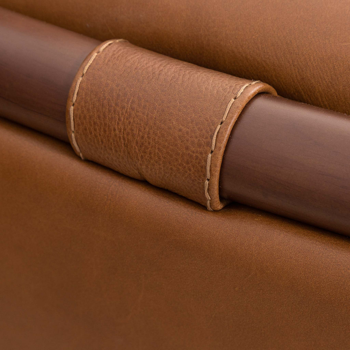 Close-up of the Leather Gallery Zuri 1 Seater Leather Couch in Czar Pecan, showing a stitched leather strap wrapped around the dark wood frame.