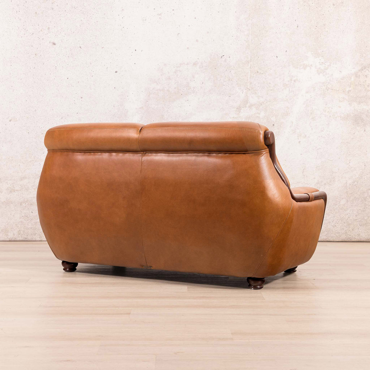 Side-rear view of the Leather Gallery Zuri 2 Seater Leather Couch in Czar Pecan, showing its leather upholstery and dark wood frame.