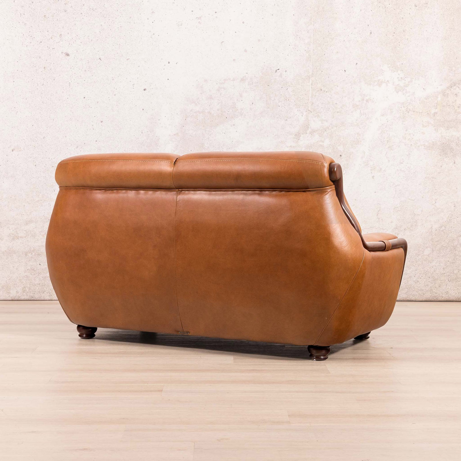 Side-rear view of the Leather Gallery Zuri 2 Seater Leather Couch in Czar Pecan, showing its leather upholstery and dark wood frame.
