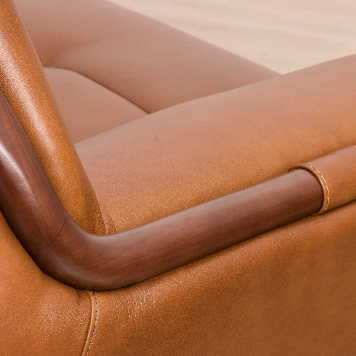 Close-up of the Leather Gallery Zuri 3 Seater Leather Couch in Czar Pecan, showing the curved dark wood armrest and visible stitching.