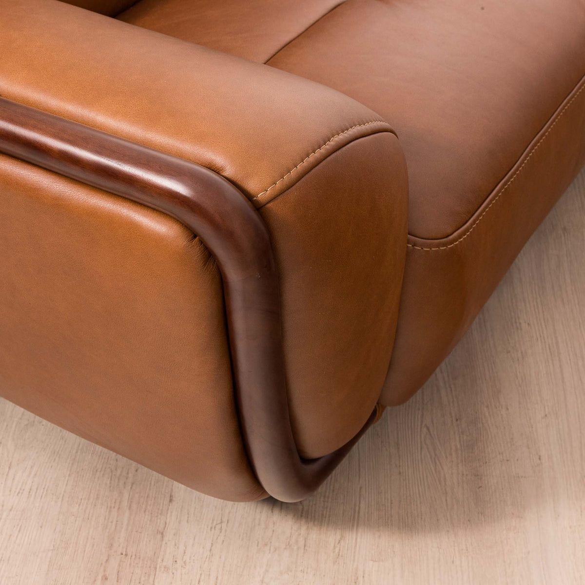 Close-up of the Leather Gallery Zuri 3 Seater Leather Couch in Czar Pecan, showing the armrest and curved dark wood trim.