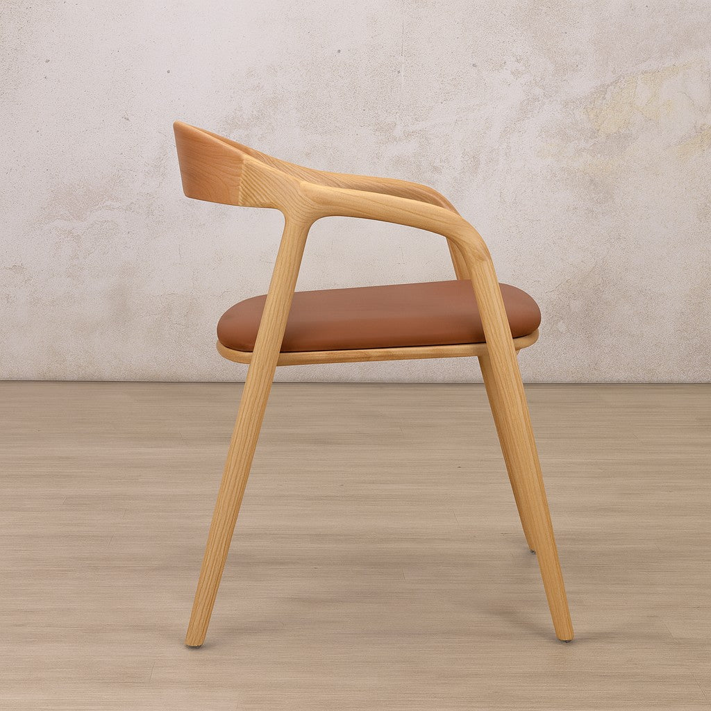 Side view of the Alaric wood dining chair with tapered legs and an ergonomic leather seat, shown from the side, in a natural finish.