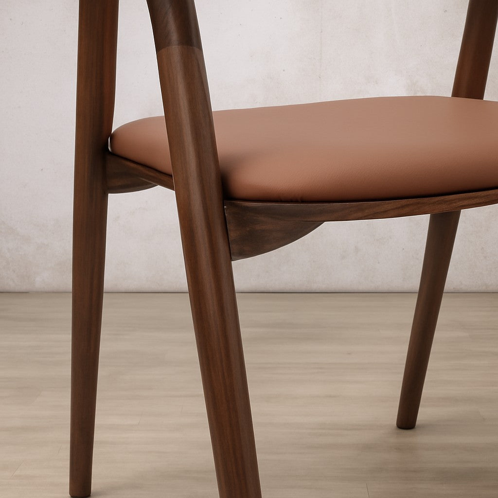 Close-up of an Alaric wooden dining chair with a light brown leather, cushioned seat. Leather dining chairs, modern dining chairs south africa