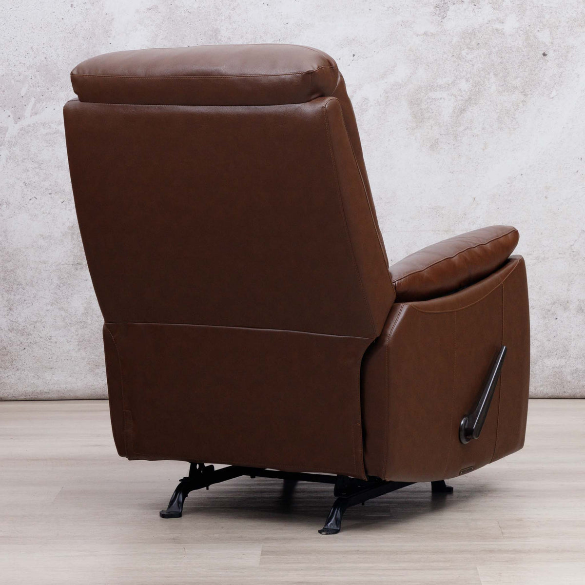 Rear three-quarter view of the Leather Gallery Dallas Leather Rocker Recliner Chair in Saddle, showing the black swivel base and manual recliner lever.
