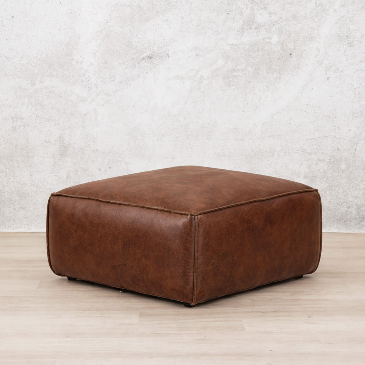 Leather Gallery Austin Leather Ottoman in Woodlands Spice, featuring rich brown leather upholstery on a light wood floor.