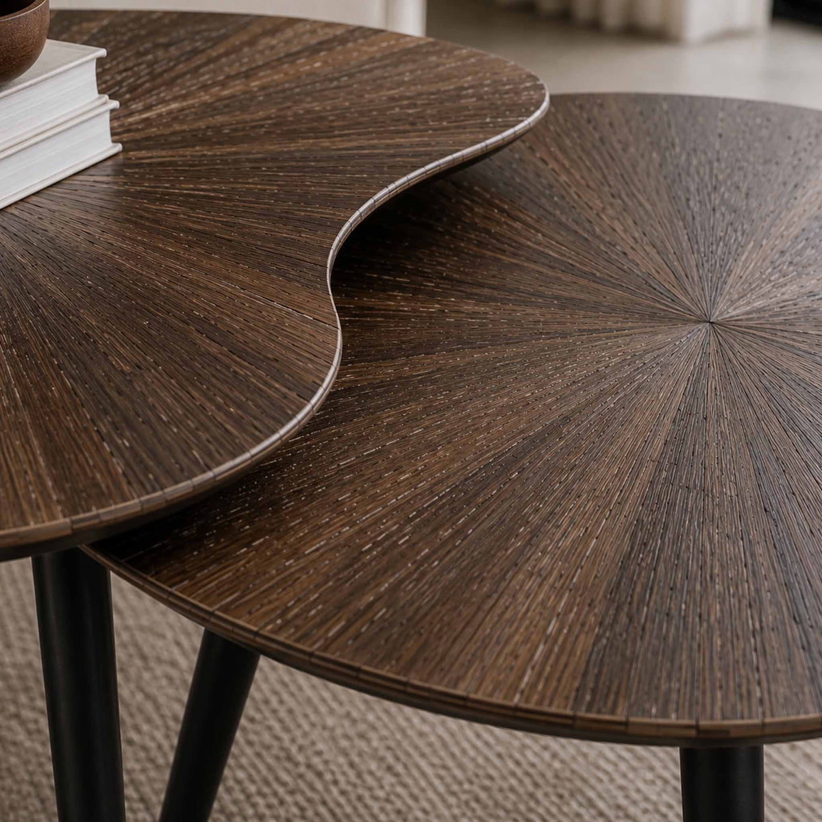 Gallery Everyday Eden Nesting Coffee Tables Set of 2, featuring dark brown sunburst wood-grain tops and black metal legs in a warm interior setting.