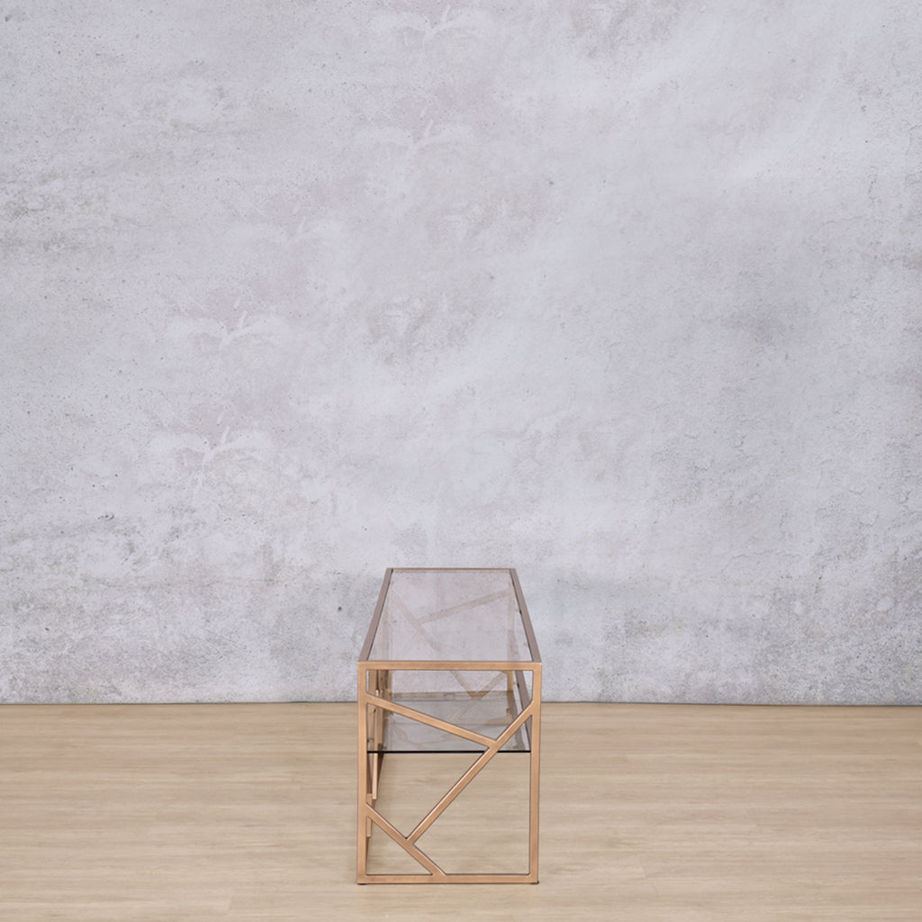 Side view of the Legacy TV Unit, showing its elegant gold mild steel base and clear glass top.