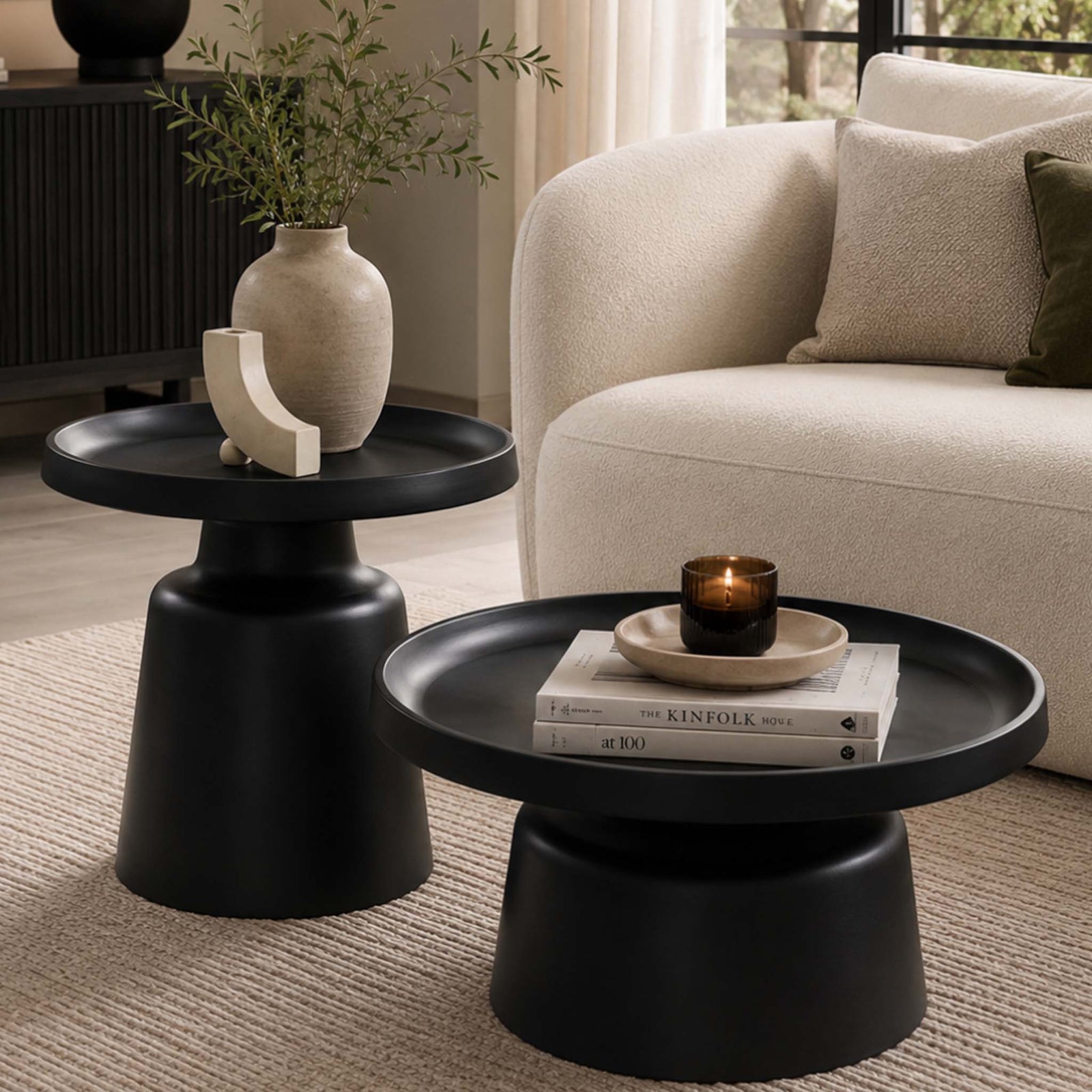 Gallery Everyday Minerva Coffee Table - Black Set of 2, featuring round pedestal tables styled with books, a candle, and a ceramic vase.