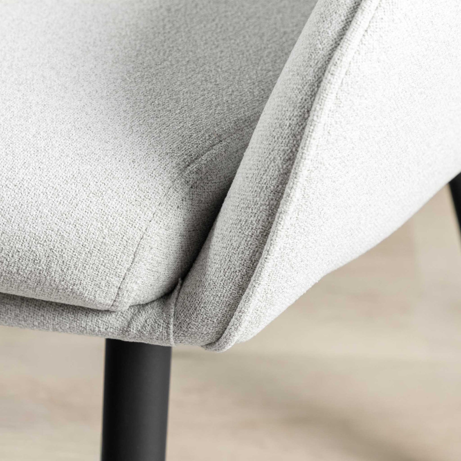 Close-up of curved armrest on Octavia light grey fabric dining chair. 