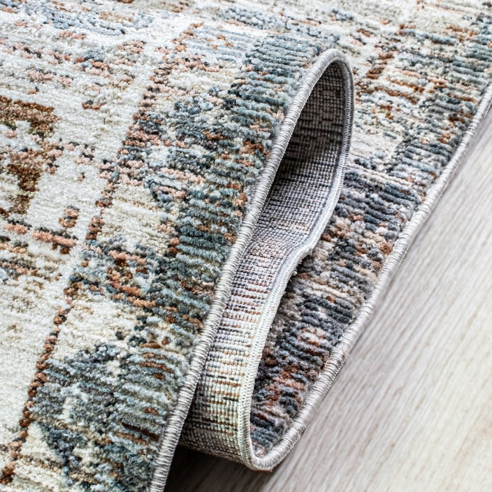 Close-up of the Leather Gallery Persia Hazey Grey Rug, showing the textured pile, bound edge, and distressed grey, cream, and rust pattern.