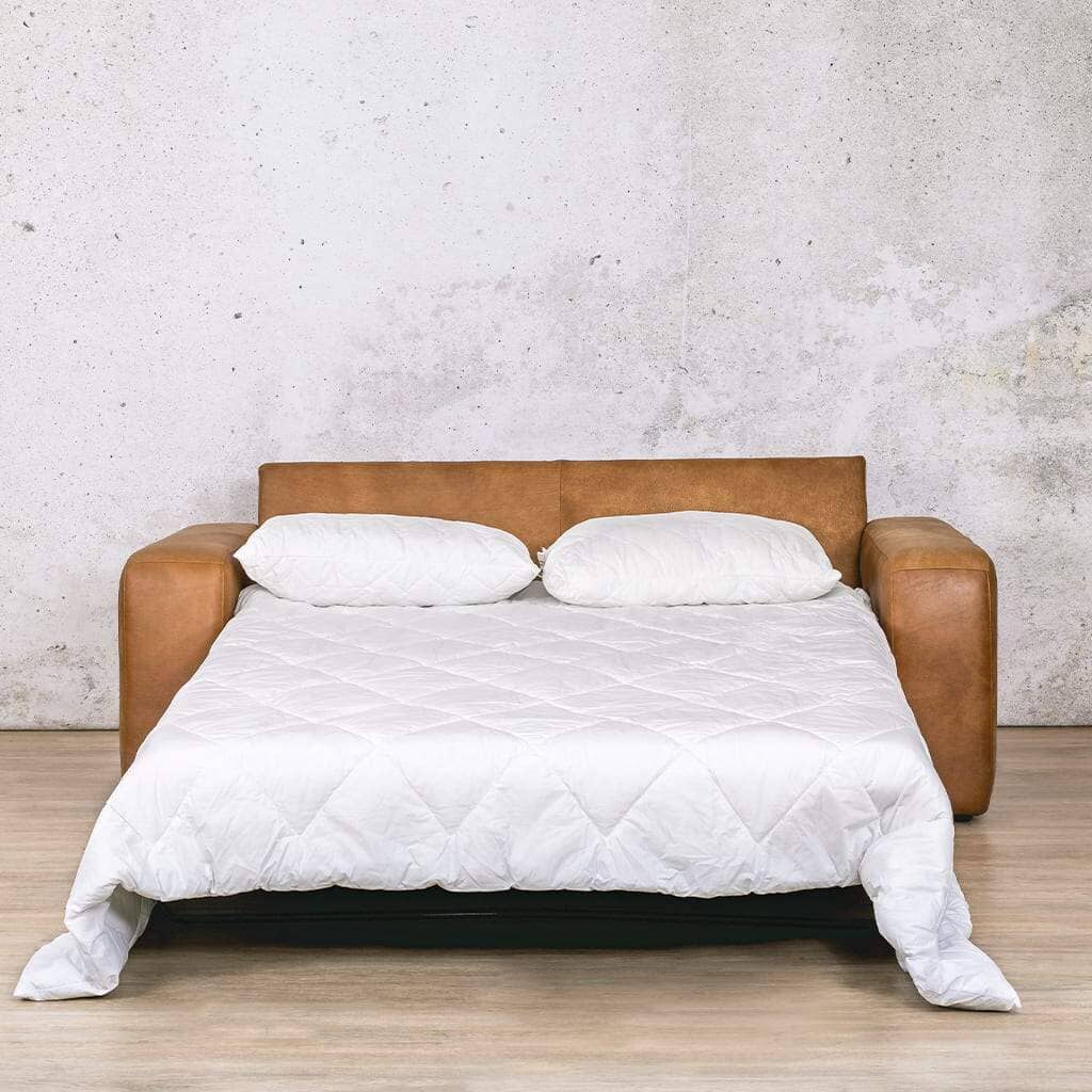 Front view of the Stanford leather sleeper couch folded out into a bed, styled with pillows for a cosy and inviting guest sleeping space. Buy Your Sleeper Couch Today from Leather Galley. Czar pecan