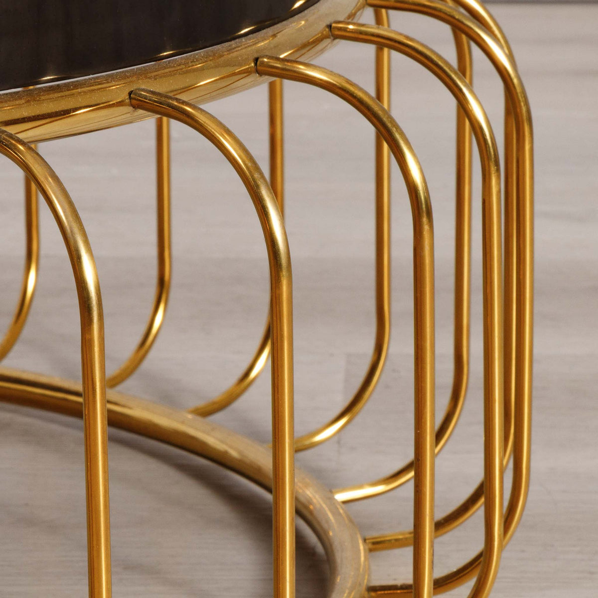 Close-up of the Leather Gallery Eve Coffee Table, showing the curved gold wire cage base and dark tabletop edge.