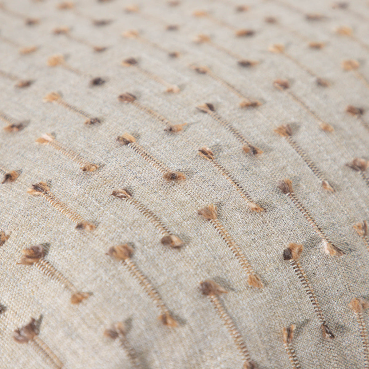 Leather Gallery Veyra Riverstone Cushion, featuring a soft neutral woven finish with delicate brown and golden stitched detailing.