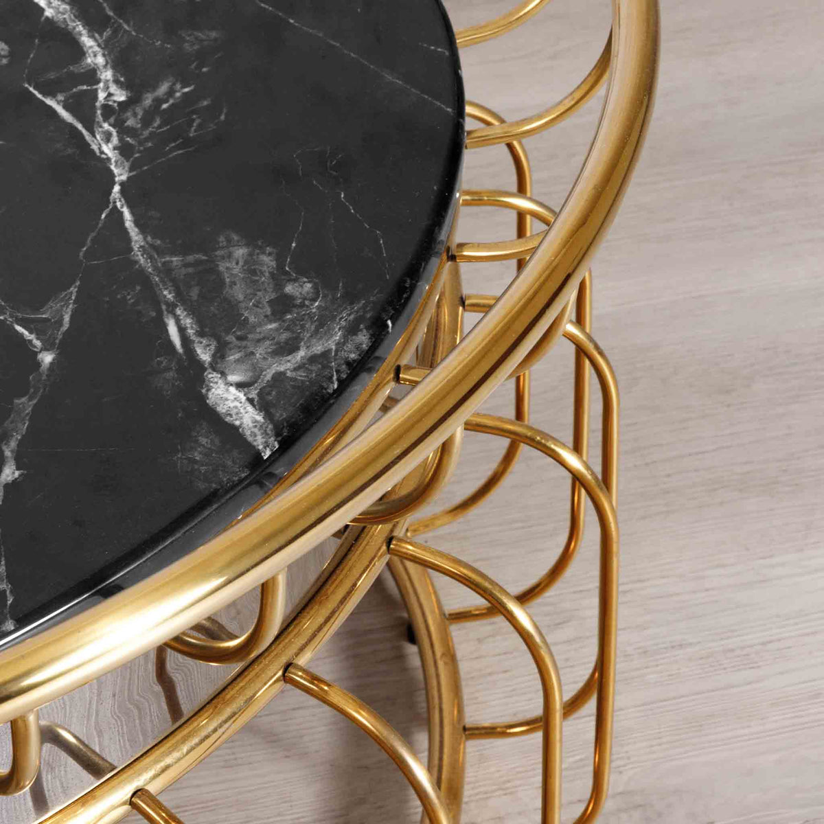 Close-up of the Leather Gallery Eve Coffee Table, showing the black marble top with white veining and curved gold wire base.