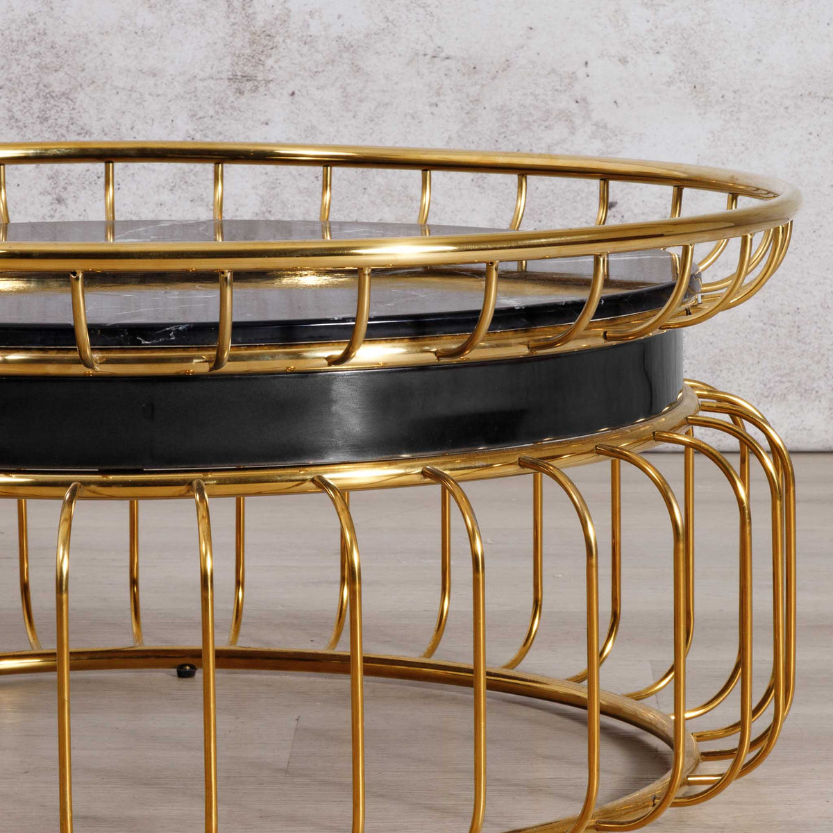 Close-up of the Leather Gallery Eve Coffee Table, featuring a black round top and polished gold wire frame.