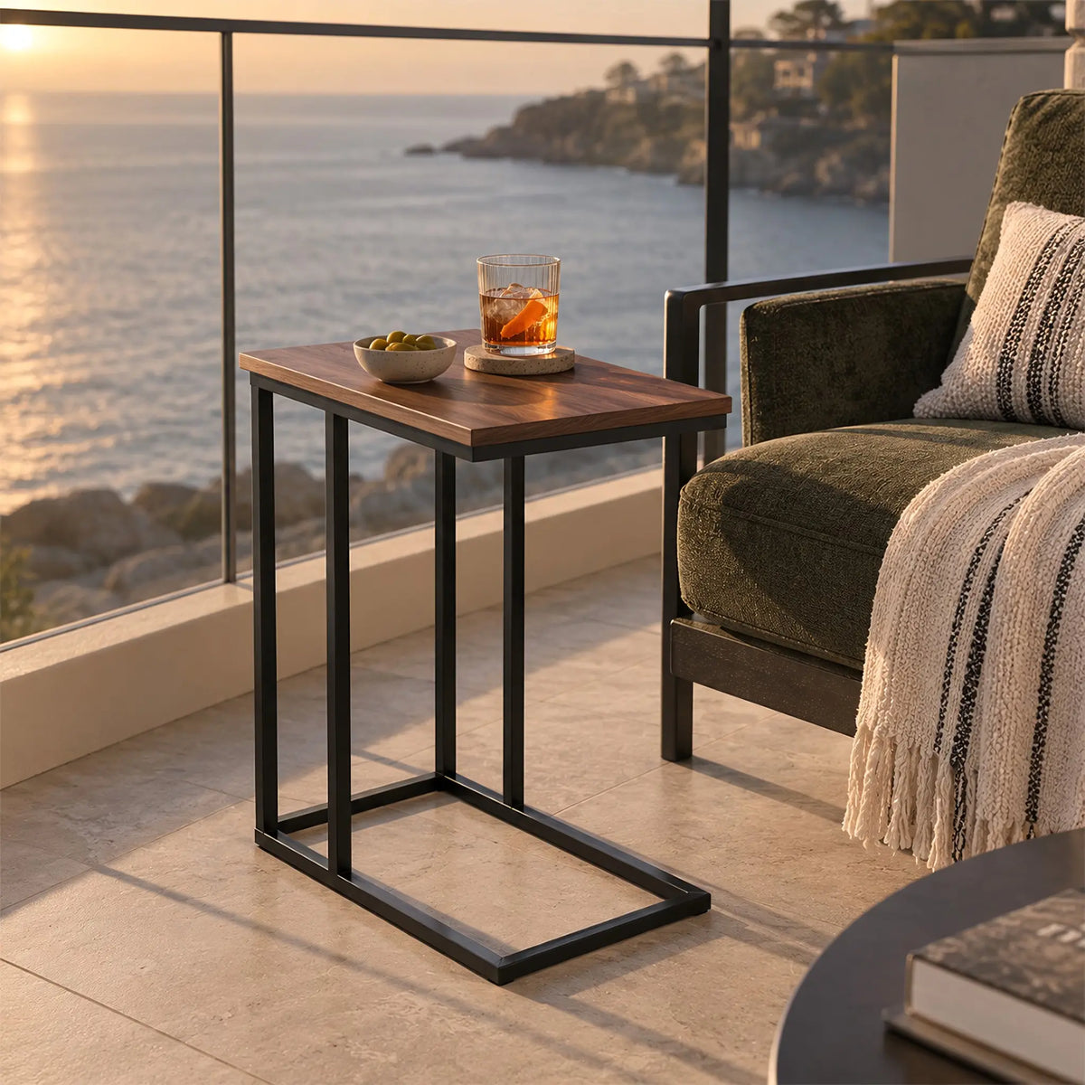 Gallery Everyday Wyatt Side Table in Brown Walnut, featuring a dark wood top and black metal frame beside an outdoor armchair.